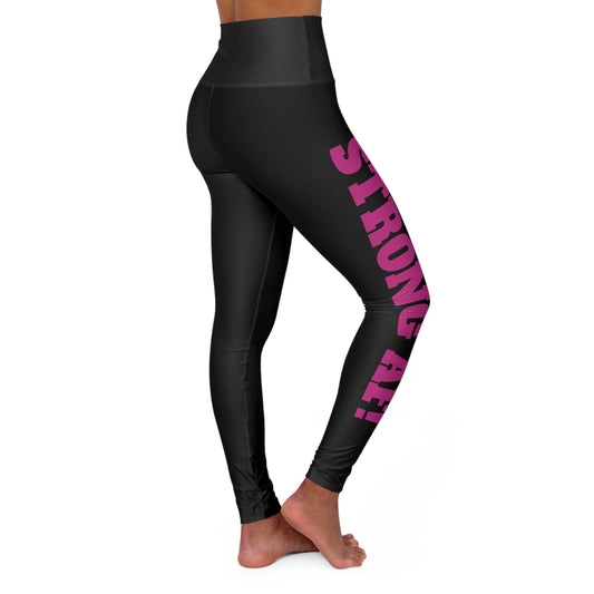 Black high-waisted leggings with bold pink text reading 'STRONG AF!' vertically down the side of the left leg, worn by a barefoot model standing in a side pose.